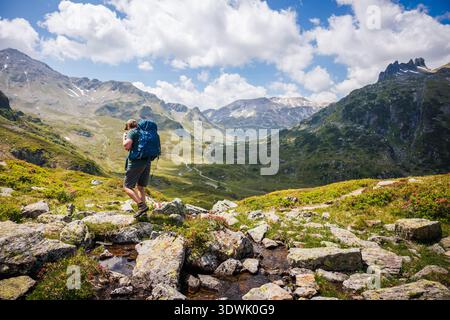 Homme avec sac à dos randonnée à travers la vallée rocheuse dans les montagnes des Alpes autrichiennes. Vacances d'été actives en Styrie, Autriche avec vue panoramique sur la montagne Banque D'Images