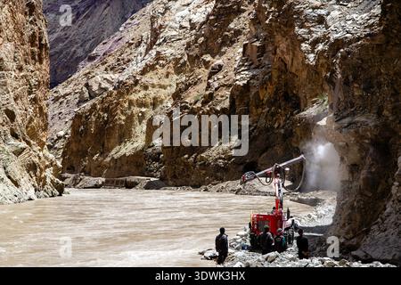 Une équipe de construction utilise de la machinerie lourde pour creuser une route à travers un terrain accidenté de montagne. Banque D'Images