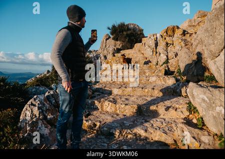Homme photographiant une jeune chèvre sauvage sur des marches de pierre à Talaia d’Albercutx Banque D'Images