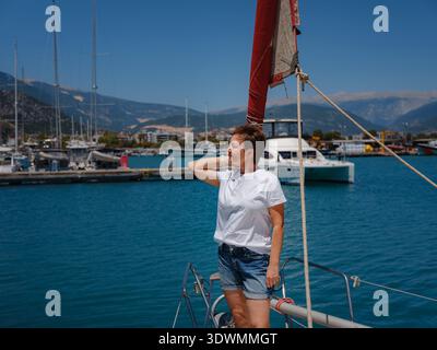 Femme marin tient le tissu de voile blanc se préparant à lever des voiles sur le yacht. L'activité physique et les compétences de manœuvre de bateau sont montrées pendant la préparation à l'as Banque D'Images