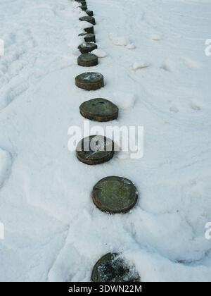 Rangée de groynes en bois dans la neige avec une forte composition linéaire et une atmosphère hivernale calme. Copyspace Banque D'Images