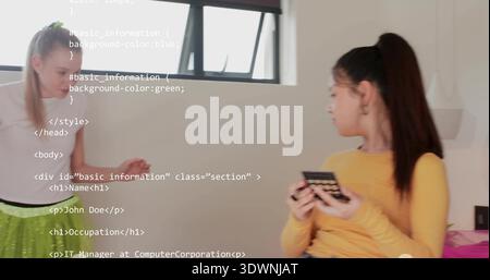 Parlant deux femmes debout, assis près de la fenêtre dans la chambre, tenant le téléphone, code HTML recouvrant le mur Banque D'Images