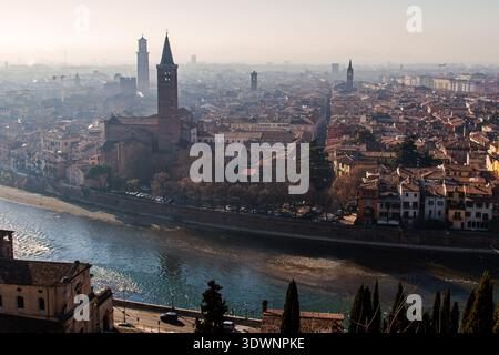 La ville historique de Vérone s'étend le long de la rivière Adige sinueuse, révélant des tours médiévales, des toits en terre cuite et des rues denses sous une lumière douce, évoquant TI Banque D'Images