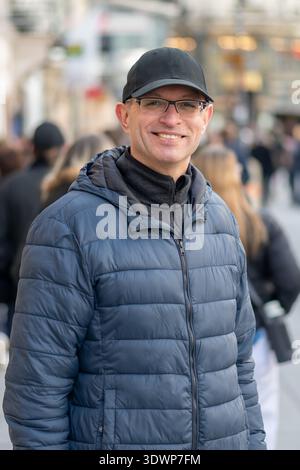 Homme souriant dans une rue animée en Europe. Banque D'Images