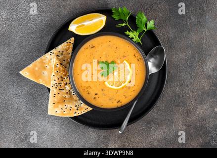 Soupe Ezogelin au citron, à la menthe séchée et aux pains plats de pide sur fond gris. Soupe de lentilles. Cuisine turque. Banque D'Images