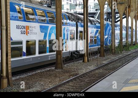 L'élégant train régional Zou bleu et blanc attend sur le quai historique sous des colonnes de fer ornées et des piliers en bois de la gare de Nice ville Banque D'Images