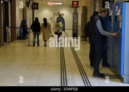 Couloir très fréquenté à la gare de Nice ville où un voyageur paie dans des casiers à bagages bleus tandis que d'autres marchent vers des quais avec des sacs et des sacs à dos. Banque D'Images