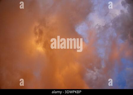 Un abstrait naturel à couper le souffle avec un mélange dynamique de nuages orange profond et bleu doux au coucher ou au lever du soleil. Le ciel affiche des textu variables Banque D'Images