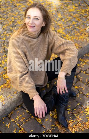 Femme élégante assise sur pavé Autumn Street Fashion Portrait Banque D'Images