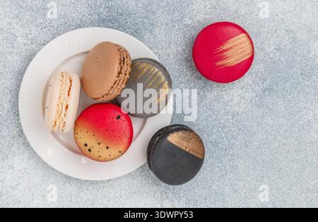 Biscuits macarons multicolores assortis sur un fond de béton gris gros plan. Biscuits sucrés aux macarons français. Désert pour les gourmets. Mise au point sélective, t Banque D'Images