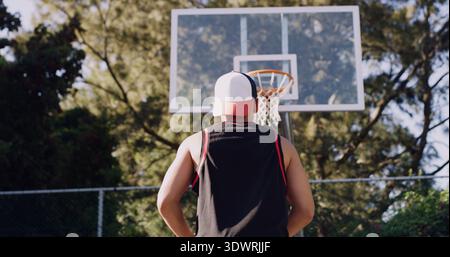 Homme, vue arrière et jouer sur un terrain de basket-ball pour le score, le point ou le match en plein air dans la nature. Actif, faible angle de la personne ou préparation avec visée ou Banque D'Images