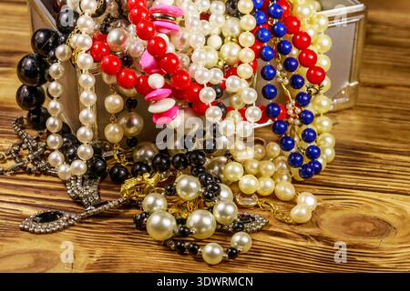 Boîte à bijoux pleine de bijoux et accessoires sur fond en bois Banque D'Images