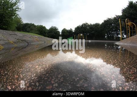 Terrain de basket-ball extérieur inondé après la pluie avec des reflets d'arbres et d'équipements sportifs dans l'eau Banque D'Images