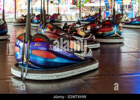 Voitures tamponneuses colorées dodgem lors d'une promenade au champ de foire, avec une voiture bleue et violette 'Ninja' numérotée 13 au premier plan. Banque D'Images