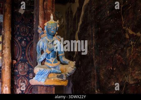 À l'intérieur du Nako Gompa, une statue bouddhiste bleue altérée se trouve devant d'anciennes peintures murales représentant diverses figures sur le mur du temple. District de Kinnaur Banque D'Images