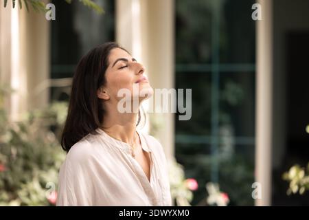 Paisible jeune femme hispanique calme prenant une profonde respiration à l'extérieur Banque D'Images
