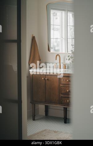 Meuble-lavabo moderne avec robinet en laiton et comptoir en marbre dans un intérieur lumineux. Banque D'Images