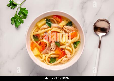 Soupe au poulet avec nouilles et légumes dans un bol blanc Banque D'Images