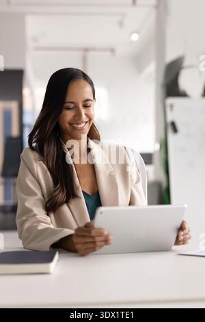 Jeune femme d'affaires attrayante travaillant sur tablette numérique sur le lieu de travail moderne Banque D'Images