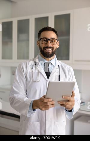 Portrait heureux médecin masculin regardant l'appareil photo tenant la tablette numérique Banque D'Images