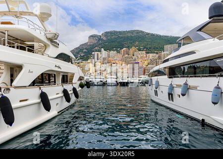 Vues de Monaco encadrées entre des super yachts de luxe amarrés au Port Hercule, la Condamine, Monaco Banque D'Images
