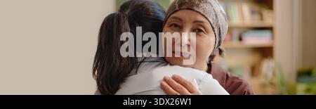 Portrait de femme asiatique d'âge moyen embrassant jeune femme adulte à l'intérieur Banque D'Images