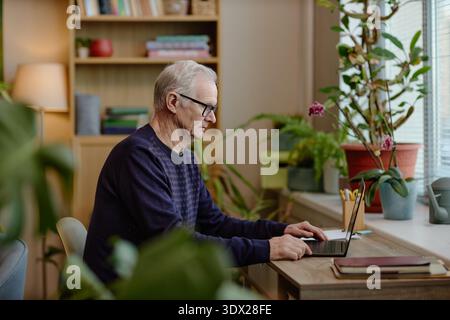 Homme caucasien senior utilisant un ordinateur portable tout en travaillant sur la recherche psychologique Banque D'Images