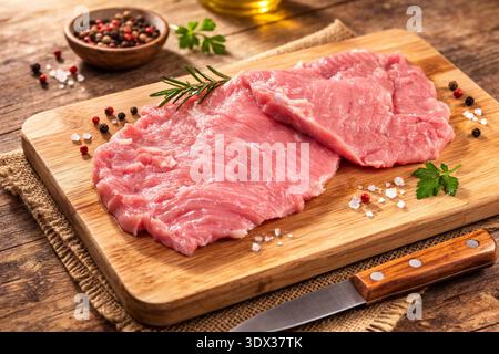 Escalopes de veau cru sur une planche à découper Banque D'Images