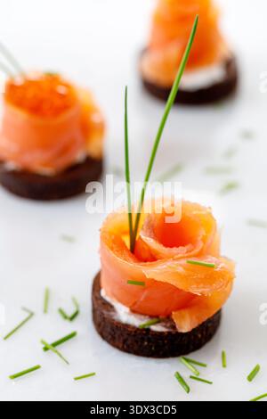 Petit toast de seigle complet avec saumon fumé salé avec gros plan d'oignon vert sur fond clair Banque D'Images