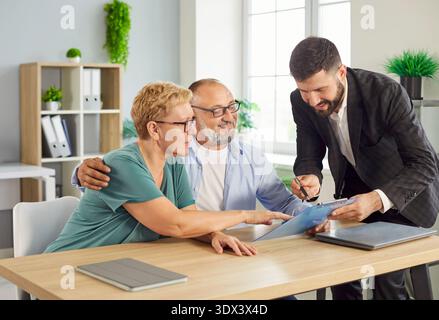 Couple senior rencontre un conseiller financier amical pour examiner les documents au bureau Banque D'Images