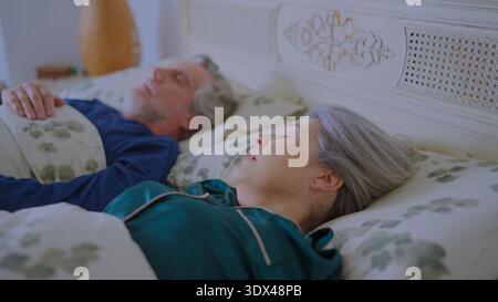 Couple senior dormant paisiblement dans le lit à la maison Banque D'Images