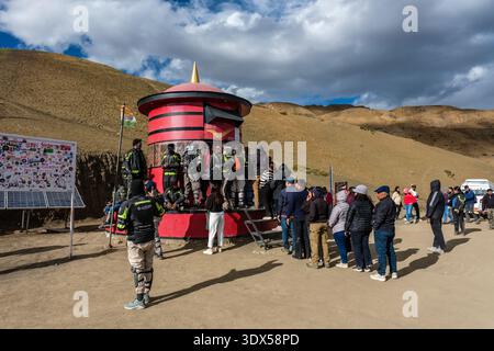 Une foule de gens se rassemble autour d'une grande boîte aux lettres cylindrique rouge au bureau de poste le plus haut du monde à Hikkim, sur une pente montagneuse aride. Banque D'Images