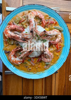Faial, Îles Açores, Portugal plaque bleue avec crevettes et riz. Les crevettes sont disposées en étoile. L'assiette est sur une table en bois Banque D'Images