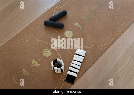 Vue de dessus de petits haltères et poids de cheville réglables placés sur un tapis de yoga en liège avec motif décoratif. Entraînement à domicile minimal et mode de vie sain Banque D'Images