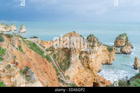 Vue imprenable sur les falaises escarpées et les eaux turquoises de Ponta da Piedade à Lagos, Portugal. Les vagues de l'océan Atlantique s'écrasent contre la forma rocheuse Banque D'Images