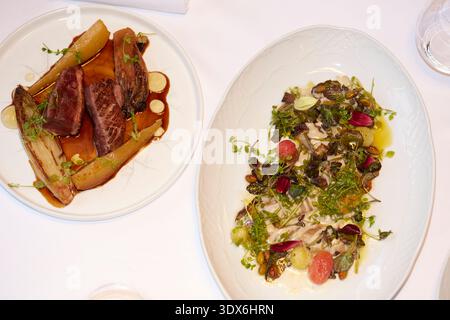 Une expérience gastronomique raffinée mettant en vedette deux plats magnifiquement présentés. Viandes parfaitement travaillées et légumes verts frais se réunissent dans un élégant Banque D'Images