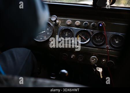 Vue rapprochée du tableau de bord d'une voiture d'époque, affichant diverses jauges et commandes. L'apparence altérée et le design classique évoquent un sentiment de nostalgie Banque D'Images