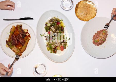 Une gamme de plats gastronomiques élégamment présentés sur une nappe blanche immaculée dans un restaurant gastronomique, mettant en valeur l'art culinaire exquis et Banque D'Images