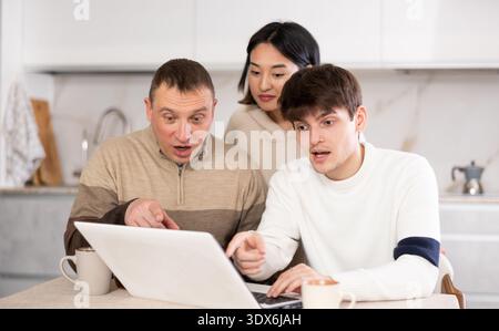 Une famille amicale regarde quelque chose ensemble sur Internet ou des chats vidéo via un ordinateur portable Banque D'Images