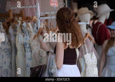 BANGKOK, THAÏLANDE-FEB 1, 2026 : voyageuse choisissant des vêtements, style de vie du marché du week-end thaïlandais, texture des cheveux, vue arrière, au marché de Chatuchak. Banque D'Images