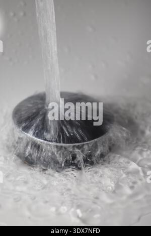 L'eau s'écoule du robinet dans le drain de l'évier Banque D'Images
