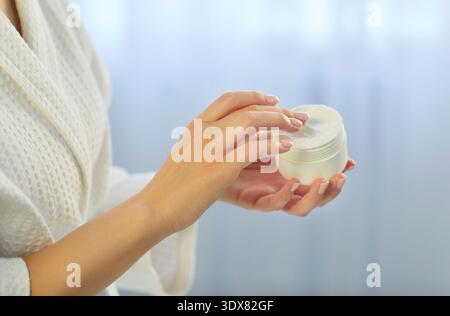 Gros plan de la femme tenant le pot avec de la crème ou de la lotion Banque D'Images