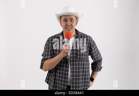 Jeune homme en chapeau chantant avec micro en studio Banque D'Images