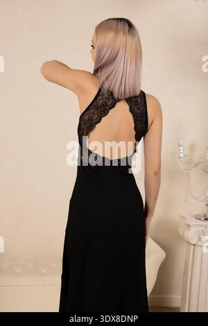 Femme en longue robe noire posant dos à la caméra Banque D'Images