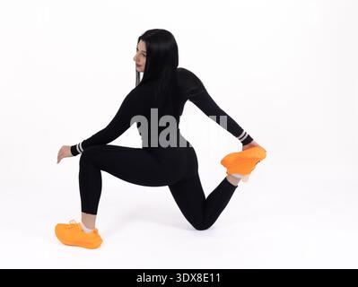 Femme en sportswear noir faisant un étirement de jambe en studio Banque D'Images