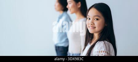 Trois individus debout dans une rangée avec une fille souriant à la caméra à l'intérieur Banque D'Images