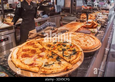 Pizza fraîchement cuite, coupée en segments - pepperoni classique, ainsi que des types combinés de quatre saisons ou assortis, où différentes garnitures sont assemb Banque D'Images