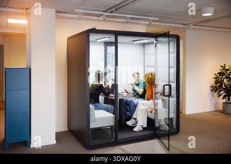 Hommes et femmes entrepreneurs assis dans la cabine de bureau pour réunion d'affaires Banque D'Images