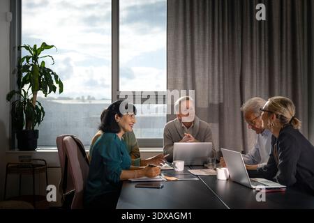 Équipe d'entrepreneurs seniors discutant tout en étant assis autour de la table dans la réunion de bureau Banque D'Images