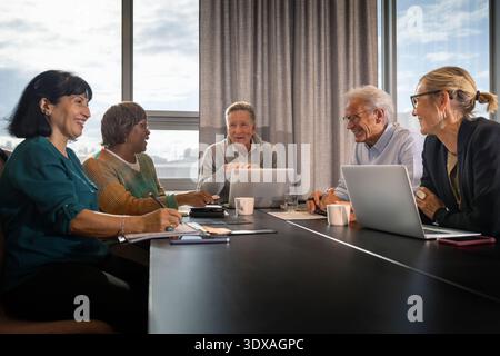Équipe de professionnels d'entreprise souriants assis autour de la table dans la salle de réunion de bureau Banque D'Images